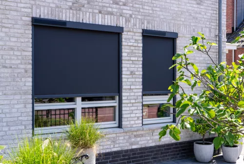 Ritsscreens op maat gemonteerd op een witte gevel, zonwering met strak doek en solar motor